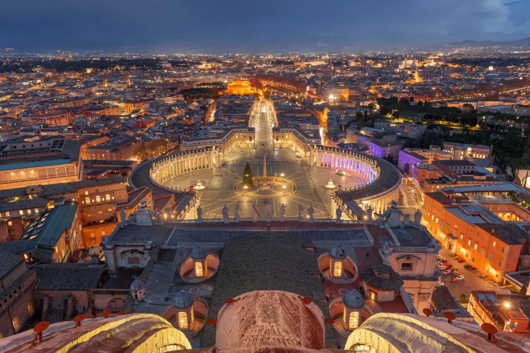Vatican City State surrounded by Rome, Italy from above at night.
